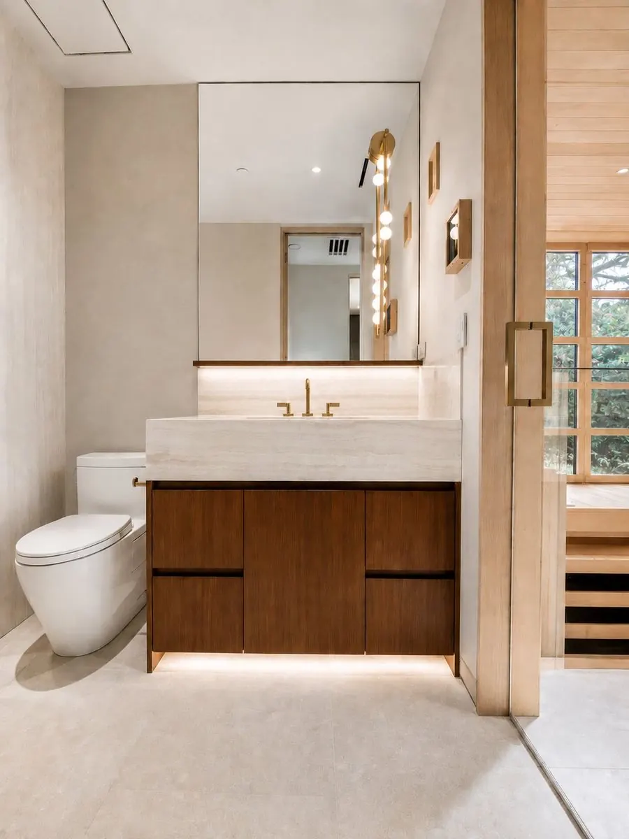 Completed modern bath with walnut floating vanity, travertine and brass fixtures in Tustin, CA by Serrano Construction